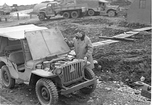 Man looks under the hood of an old jeep from world war two.jpg